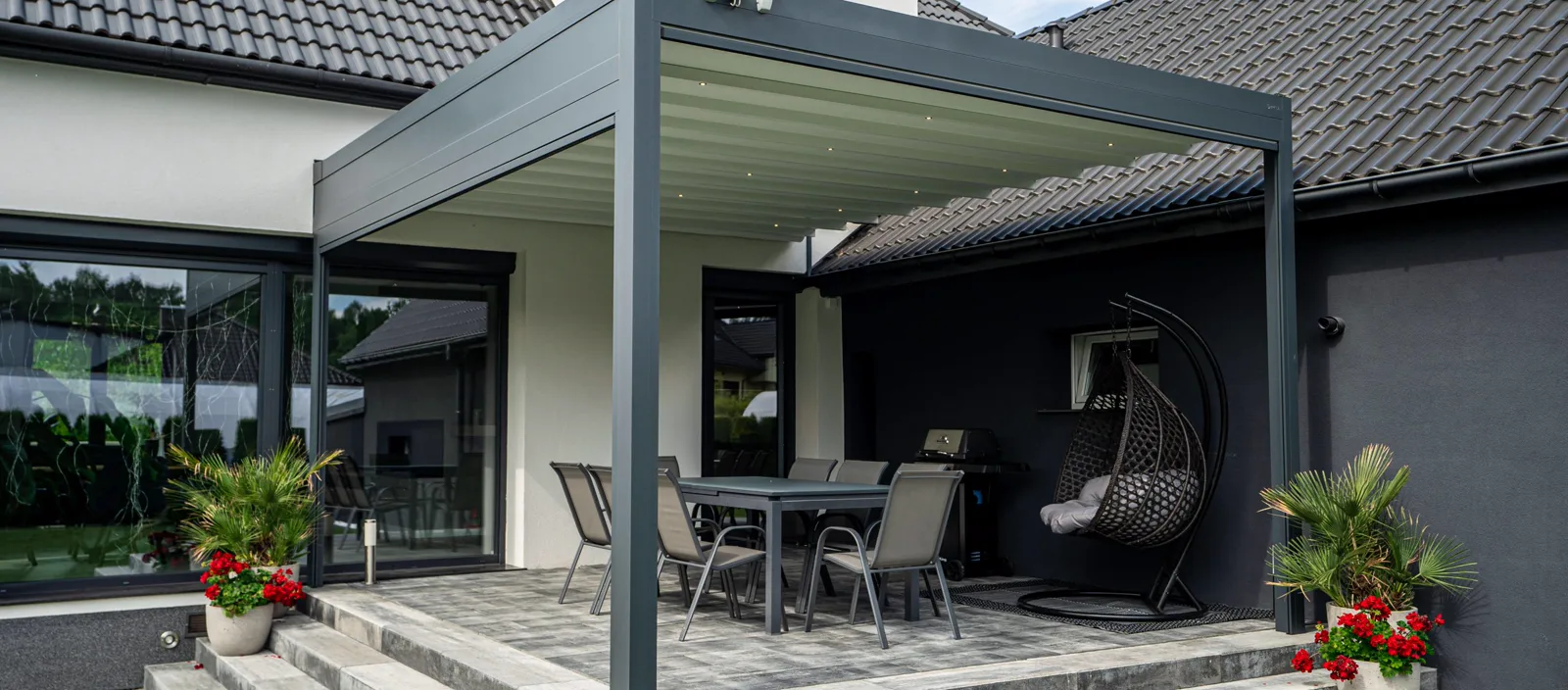 Faltpergola Milano über erhöhter Steinterrasse mit Essbereich