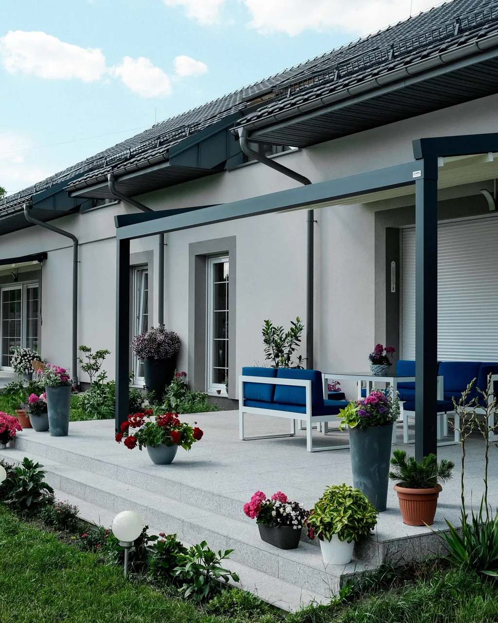 Faltpergola Portofino von Surma mit geneigtem Faltdach an klassischem Haus, RolloMax Wien