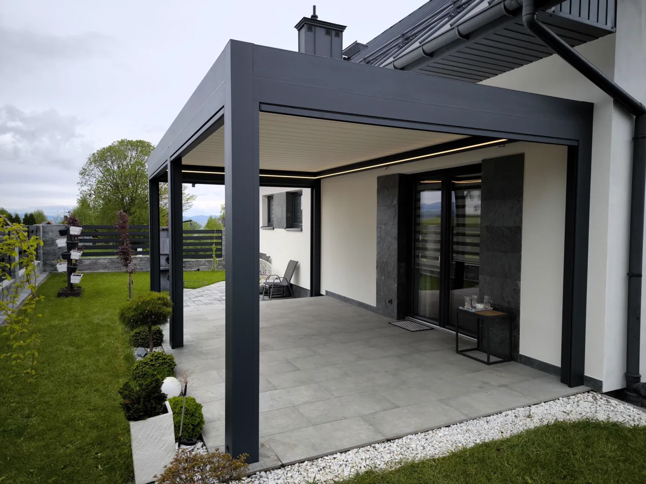 Wandmontiertes Lamellendach Toscana mit LED-Beleuchtung an Einfamilienhaus