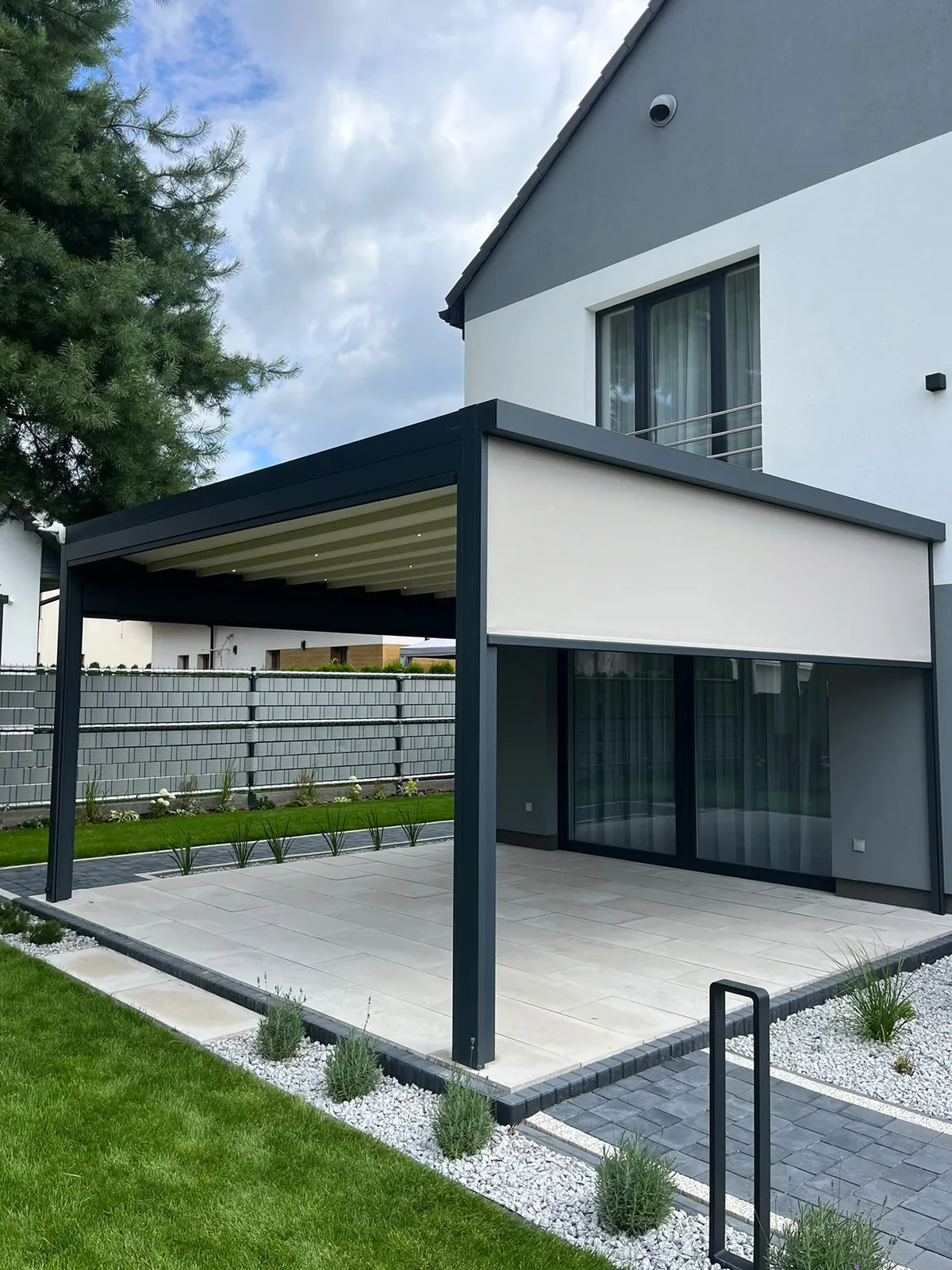 RolloMax Faltpergola Milano mit seitlicher ZIP-Beschattung an einem modernen Einfamilienhaus