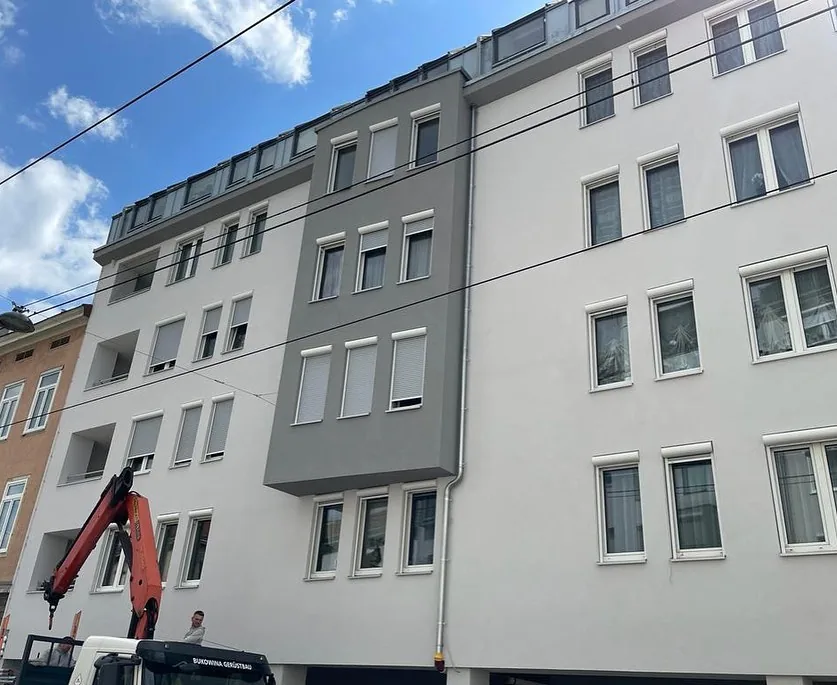Sanierte Wiener Wohnhausfassade mit neuen Rollläden von RolloMax