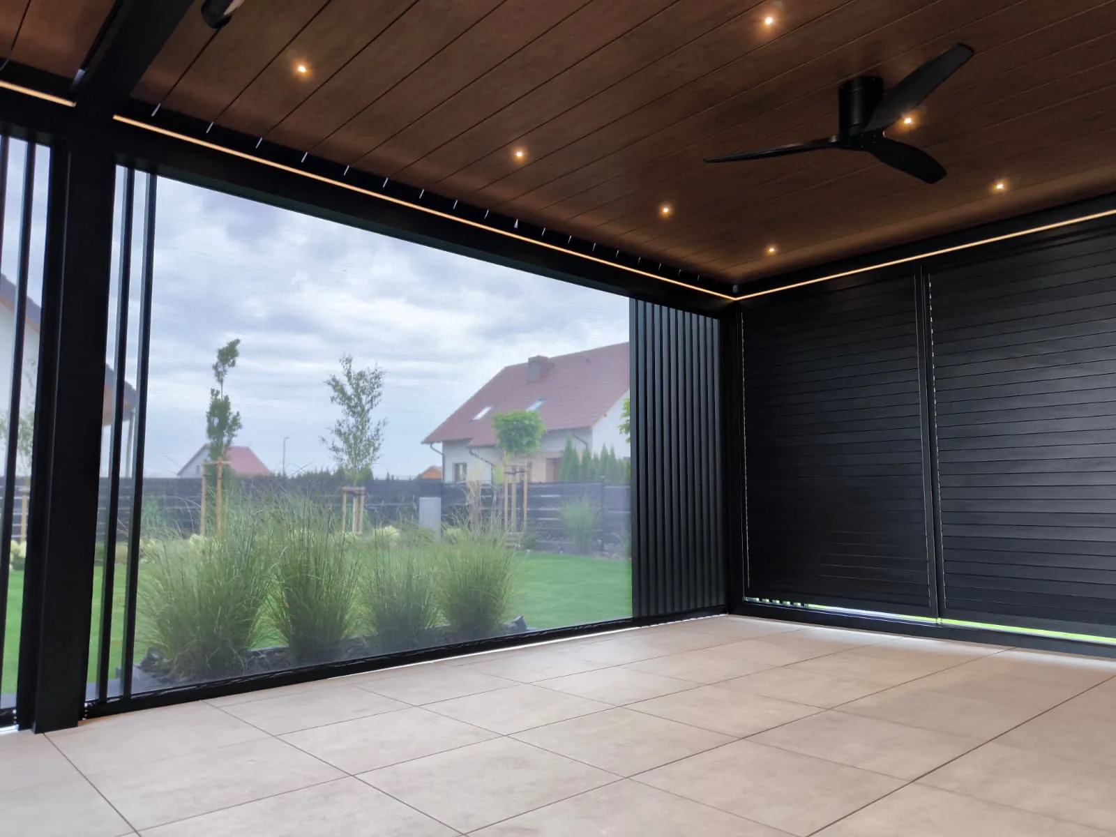 RolloMax Lamellendach Toscana mit Deckenventilator und LED-Spots über einer Terrasse